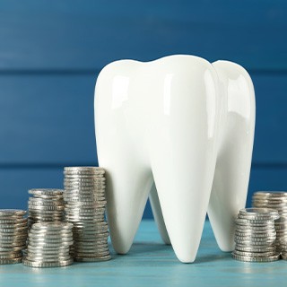 A large model tooth surrounded by stacks of silver coins