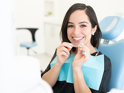 Smiling woman holding clear aligner